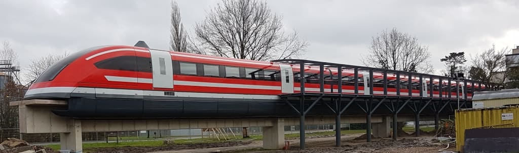 Ein roter Transrapid-Zug auf seiner Trasse.