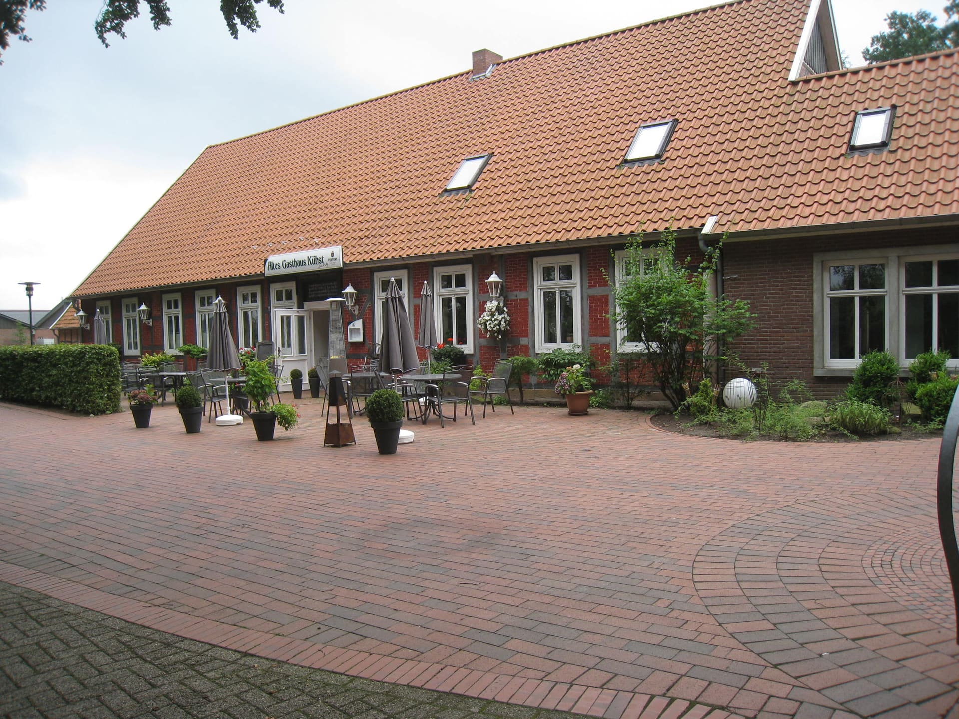 Das Heimathaus von der Hofseite, mit Pflanzkübeln und Laternen auf dem Pflaster.