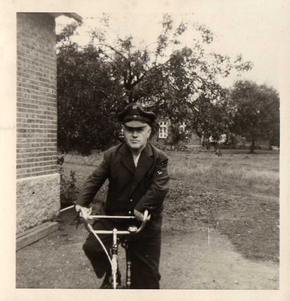 Alte Fotografie: ein Mann in Uniform und Mütze auf einem Fahrrad.
