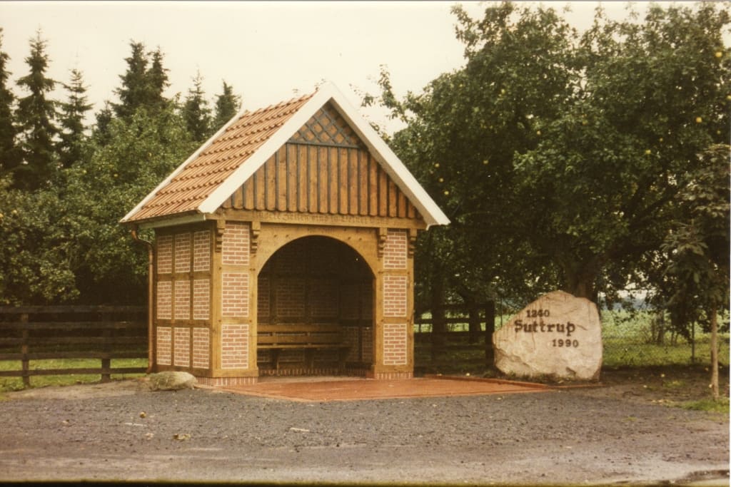 Hölzerner Unterstand und ein Findling mit der Aufschrift „Suttrup“.