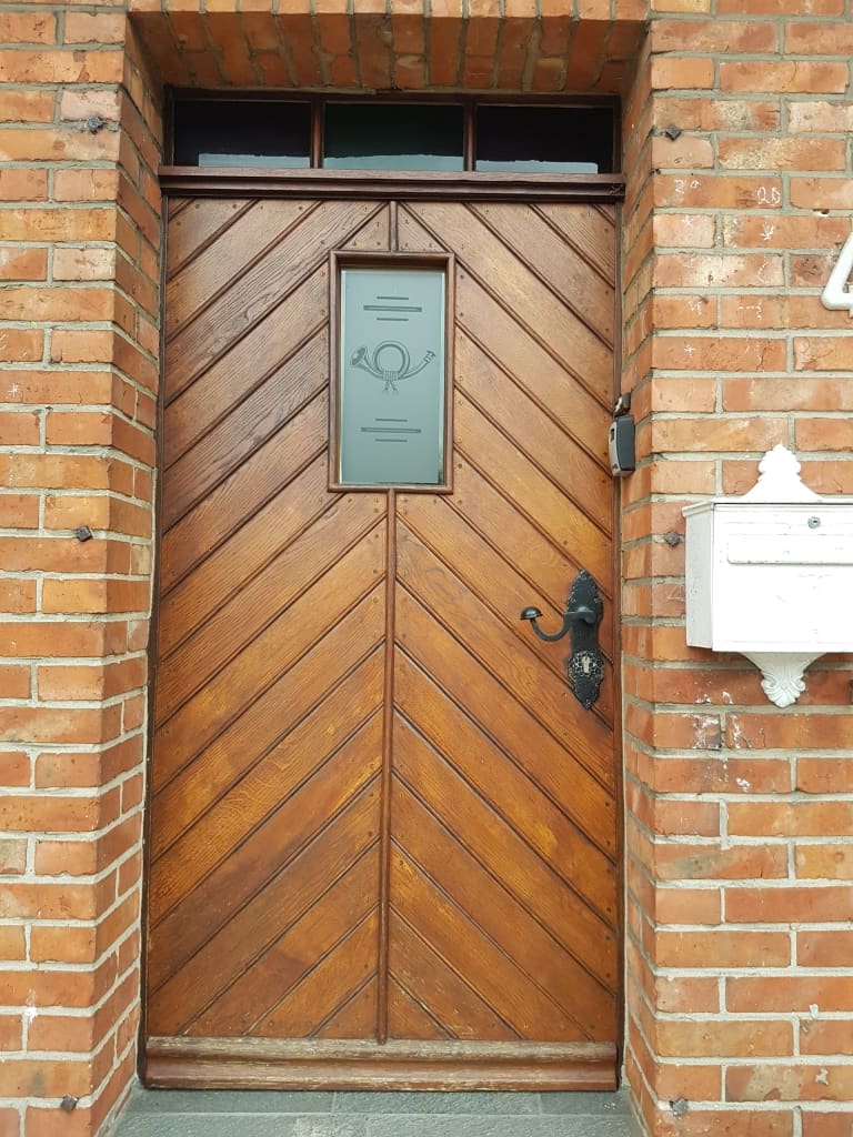 Holztür in einer Backsteinwand mit Posthorn-Schild.